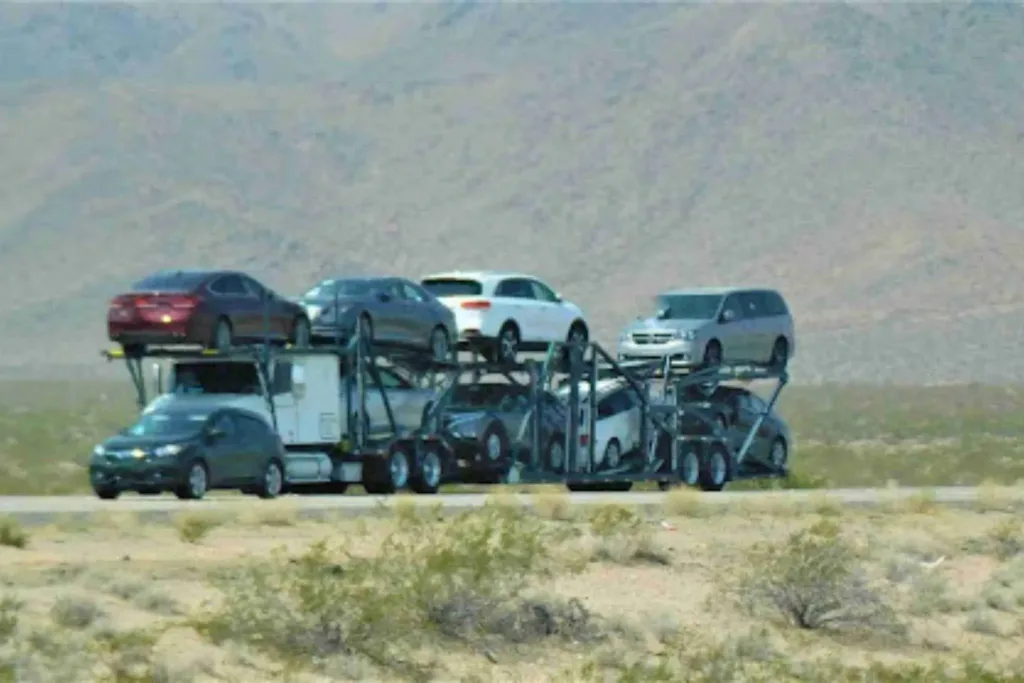 Multi-car carrier truck hauling vehicles on a highway, showing truck transport side of truck vs rail car shipping. Multi-car carrier truck hauling vehicles on a highway, showing truck transport side of truck vs rail car shipping.
