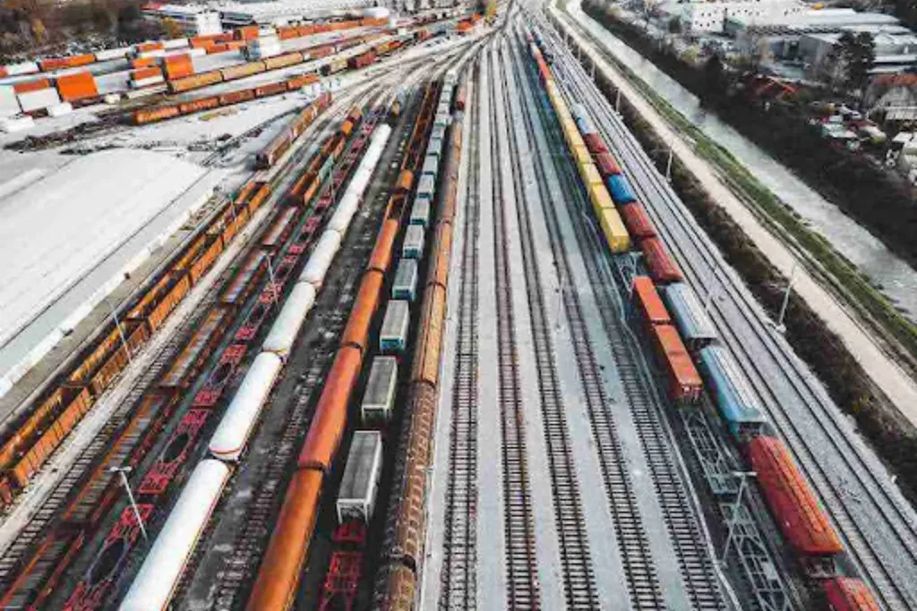 Truck vs Rail Car Shipping: What Long-Distance Really Costs Aerial view of a busy rail yard with freight trains, highlighting scale and efficiency in truck vs rail car shipping.