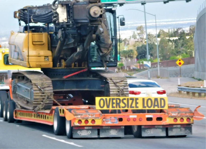 Shipping oversized vehicles with heavy construction equipment secured on an oversize load trailer