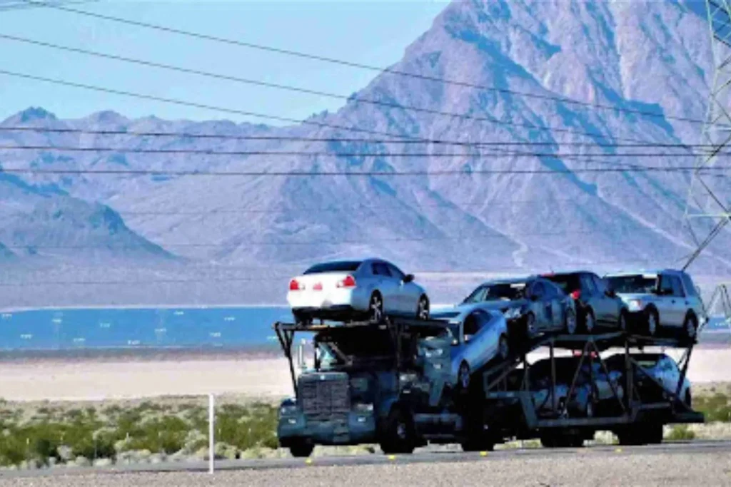 Auto Transport Broker vs Carrier: What’s the Difference? Multi-vehicle auto carrier driving through desert landscape, representing the carrier side in broker vs carrier transport.