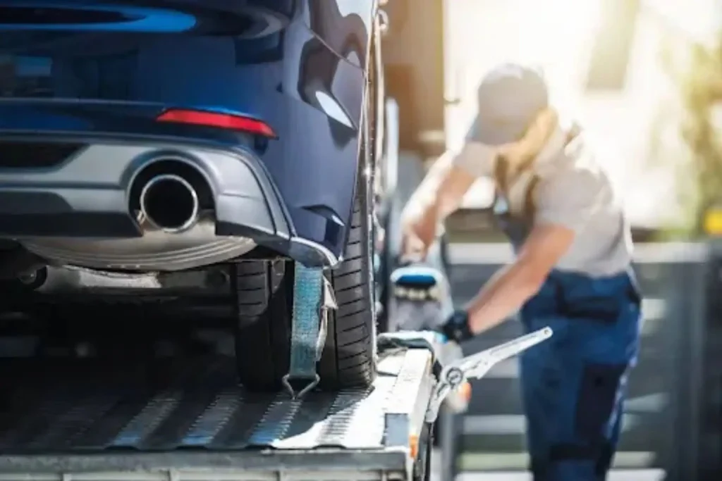 Shipping a Car Bought Online: What Happens After You Buy Driver securing vehicle on trailer during pickup process for shipping a car bought online to a new location.