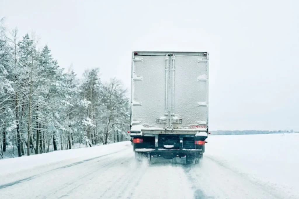 The Snowbird’s Guide to Shipping Your Car to Florida (and Back) Transport truck driving on icy road reflecting challenges in snowbird car shipping to Florida from colder states.