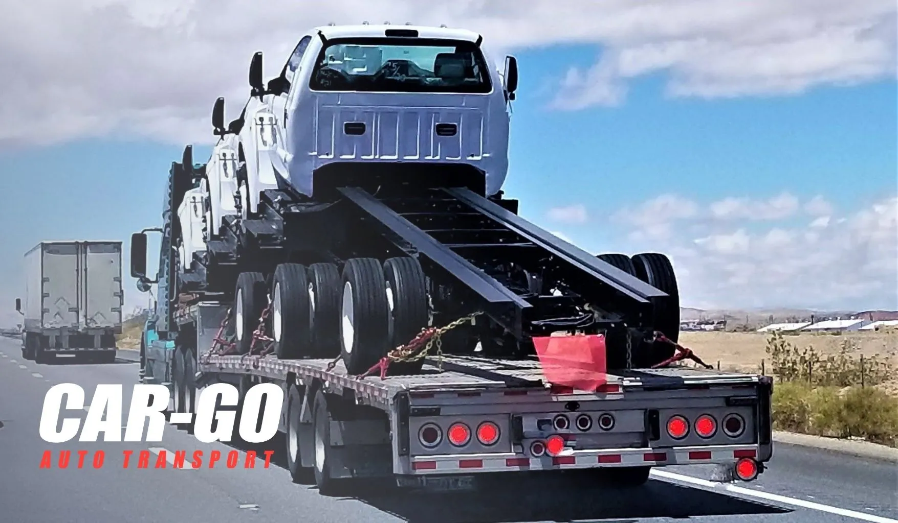 ship-car-out-state-trucks Ship car to out of state buyer with a flatbed carrier hauling multiple truck chassis on an interstate highway.